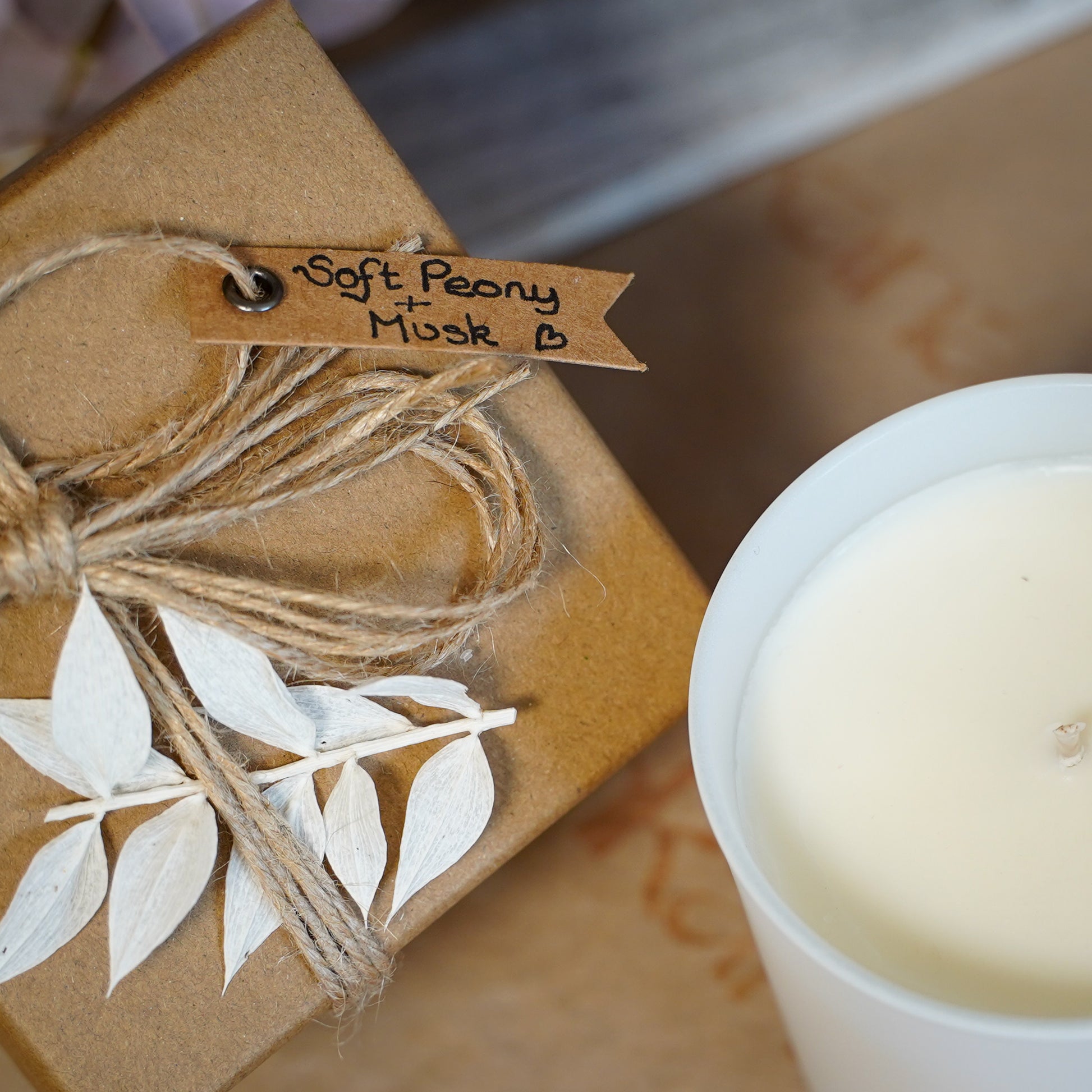 top view of box with label and oshkana vegan soy wax candle peony musk